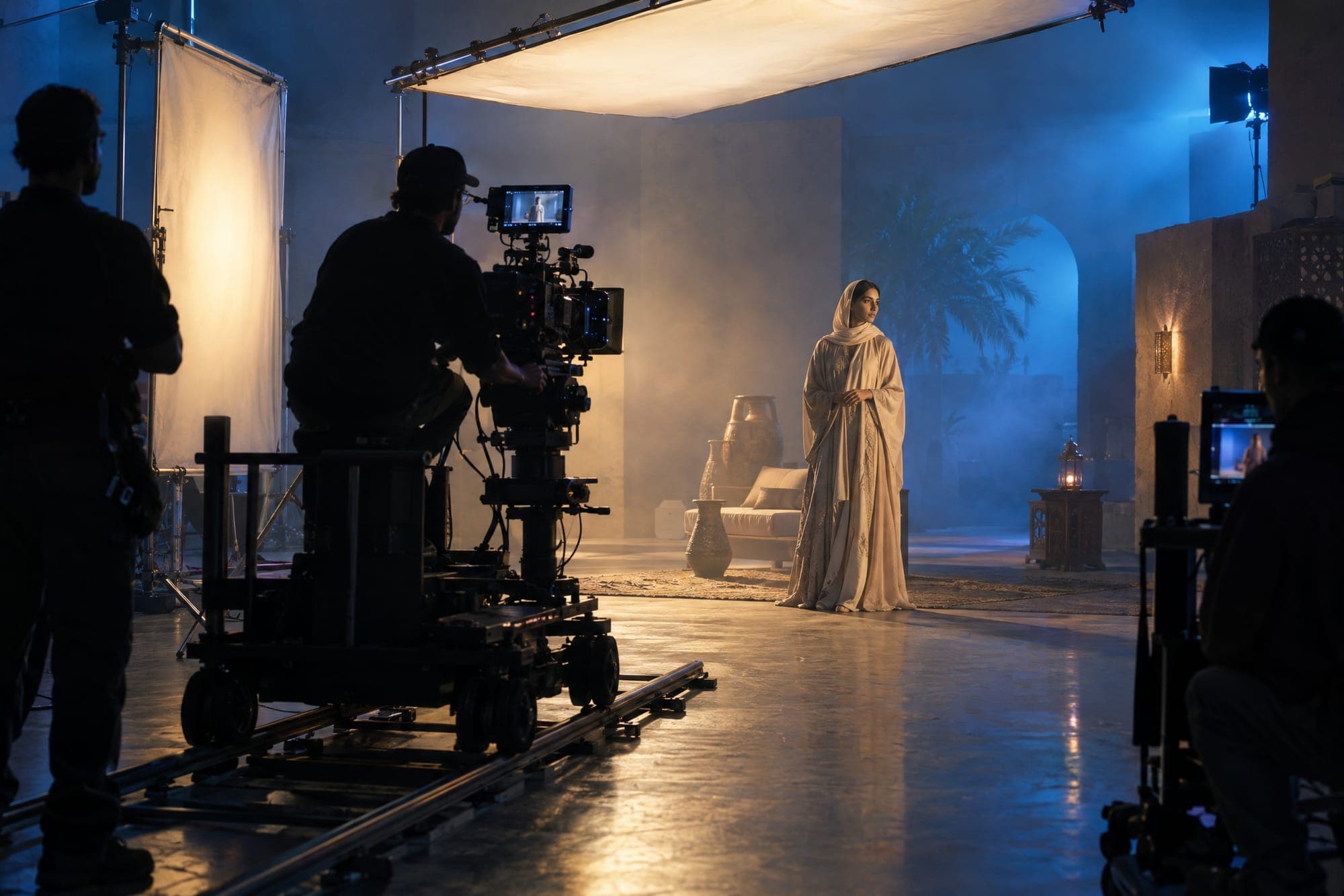 Film crew lighting a scene on a studio set with a soft cinematic grade